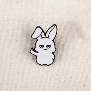 Gros plan d'un pin's lapin blanc en émail avec un geste de doigt d'honneur sur toile
