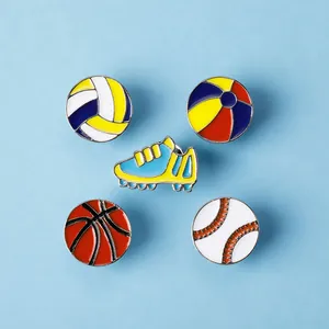 Nahaufnahme von fünf Sport-Emaille-Pins mit Fußball-, Basketball- und Baseball-Motiven