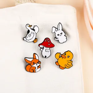 Cinq pin's émaillés cartoon avec oie et champignon sur un sac en toile blanc