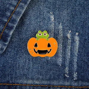 Cute frog in Halloween pumpkin enamel pin badge on blue denim fabric