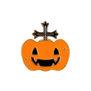 Halloween enamel pin with orange pumpkin design and black golden cross detail on white backdrop