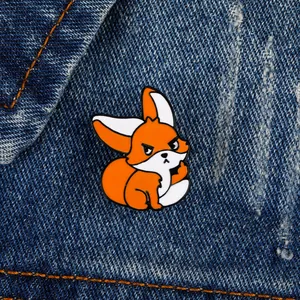 Détail d'un pin's renard orange rebelle en émail sur un tissu en jean bleu foncé
