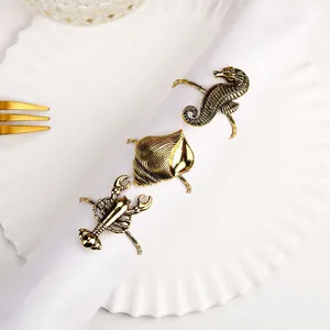 Primer plano de servilleteros de metal dorado vintage con caballito de mar y langosta