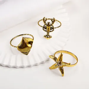 Detalle de los servilleteros dorados de langosta, caracola y estrella de mar con brillo