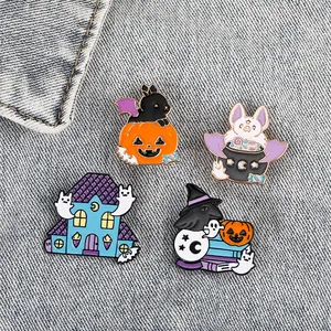 Close-up of four Halloween enamel pins featuring ghosts and black cats on denim fabric