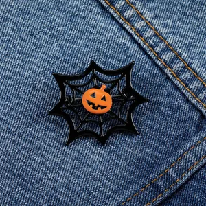 Detail of Halloween pumpkin head brooch with black spider web on denim fabric background