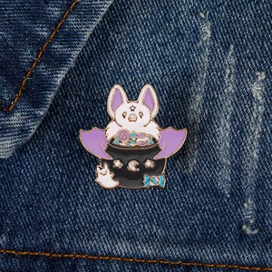 Detail of Halloween enamel pins with bats and ghosts on blue denim fabric