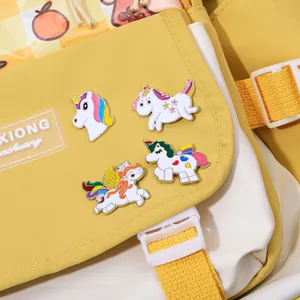 Detailed close-up of colorful enamel unicorn pins attached to a yellow canvas bag