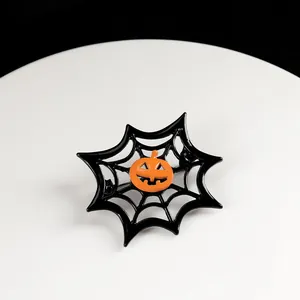 Macro shot of a Halloween pumpkin brooch featuring an orange face and black spider web frame