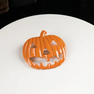 Close-up of orange Jack-o'-lantern pumpkin brooch with glossy enamel finish on a white tray