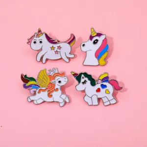 Close-up of four colorful unicorn enamel pins in various designs on pink background