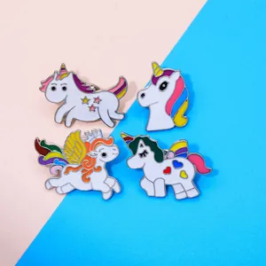 Detail showing four colorful unicorn enamel pins with rainbow hair on a pastel background