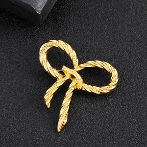 Macro detail of a golden twisted rope bow brooch with a polished metallic finish