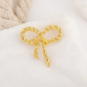 Macro detail of a golden bow brooch with rope texture pinned on a canvas bag fabric