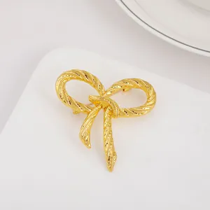 Detailed close-up of a vintage golden bow brooch with elegant twisted rope texture finish