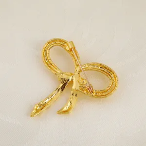 Detailed back view of gold bow brooch showing the secure pin fastener and metal texture