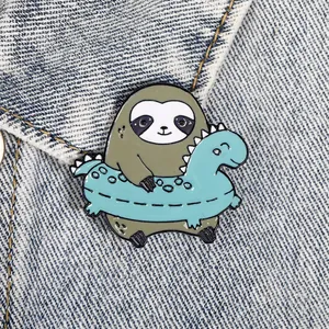 Macro shot of sloth in dinosaur swimming ring enamel pin on blue denim fabric