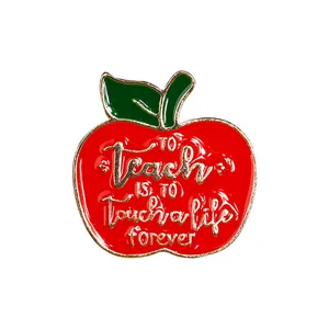 Detail showing red enamel apple pin with engraved golden quote for teacher gifts