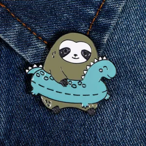 Cute cartoon sloth in dinosaur swim ring enamel pin on dark blue denim fabric background