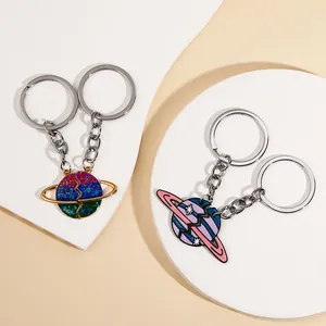 Detailopname van in elkaar grijpende planeetsleutelhangers met glitter en emaille