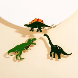 Detaillierte Nahaufnahme von drei bunten Dinosaurier-Emaille-Pins für Rucksäcke