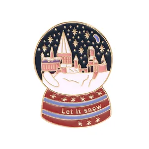 Detailed close-up of enamel crystal ball brooch with castle design and Let it snow text