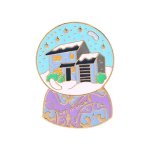 Detailed close-up of a snow globe enamel pin with Let it snow text and winter landscape