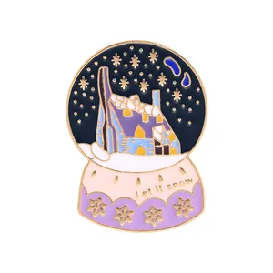 Detail of Let it snow crystal ball enamel pin with winter house and snowy scene