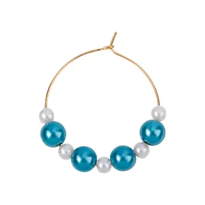 Golden round hoop earrings with alternating blue and white pearls on white background