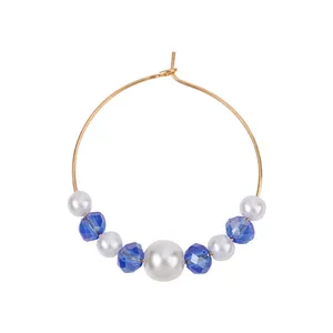 Detailed view of gold hoop earring with white pearls and blue faceted bead accents