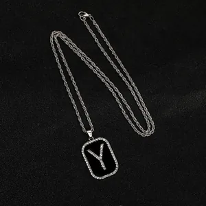 Detalle de cadena de cordón plateada y colgante rectangular con letra Y de diamantes