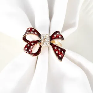 Detailed close-up of a red enamel bow napkin ring with gold plating and sparkling crystals