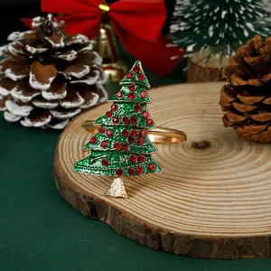 Detail van kerstboom servetring met groen email en rode strassteentjes op hout
