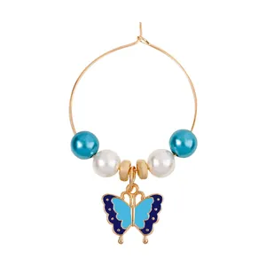 Golden hoop earrings with blue and white pearls and a butterfly enamel pendant