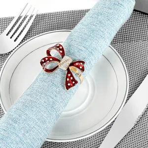 Close-up of red enamel bow napkin ring with gold edges and rhinestones on a blue napkin