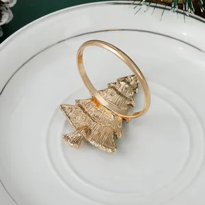 Detail van een gouden kerstboom servetring op een wit bord met kerstdecoratie