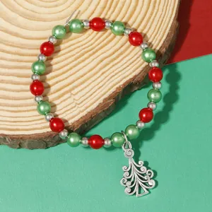 Detail of Christmas beaded wine glass charm with silver Christmas tree pendant on wood