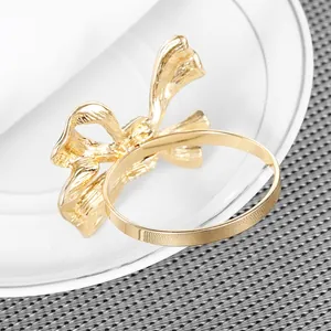 Elegant gold bow napkin ring set on a white ceramic plate for formal table decor