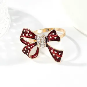 Elegant gold napkin ring with a large red bow featuring sparkling white rhinestones
