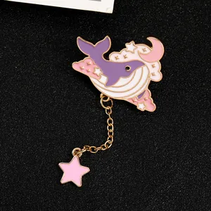 Detailed view of enamel whale brooch with pink clouds, golden moon and hanging star