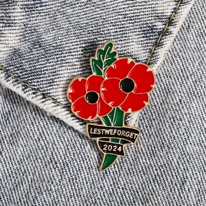 Broche en émail coquelicot avec texte 'Lest We Forget 2024' sur tissu denim bleu