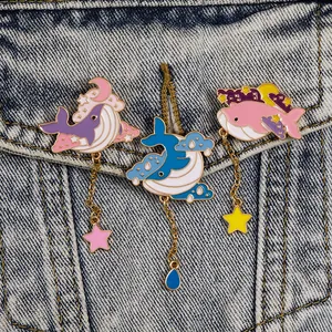 Close-up of enamel whale brooches with hanging star pendants on denim jacket