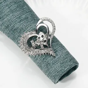 Macro shot of silver heart napkin ring with sparkling crystals on green fabric