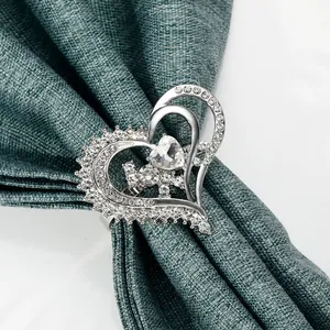 Elegant silver heart napkin ring with sparkling crystals on dark green fabric backdrop