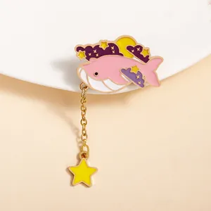 Cartoon pink whale enamel brooch with golden chain and star charm on beige background