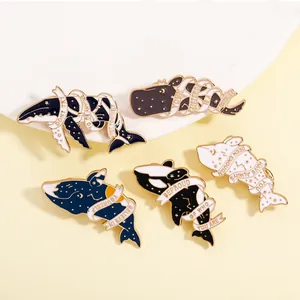 Detail of enamel whale and dolphin brooches with inspirational gold lettering
