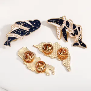 Macro shot of gold enamel whale brooches showing star patterns and butterfly pin clutch backings