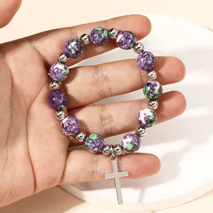 Detail of beaded religious bracelet with purple stone beads and silver cross pendant
