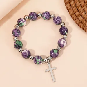 Detail of natural stone beads stretch bracelet with polished silver cross pendant