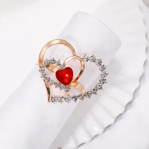 Golden heart napkin ring with sparkling red gemstones and crystal accents on a white cloth